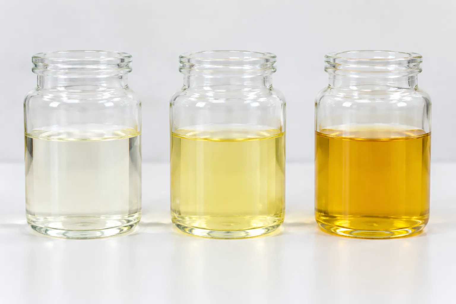 Three clear glass jars of alkyd resin showing fresh pale color, storage yellowing, and aged amber discoloration